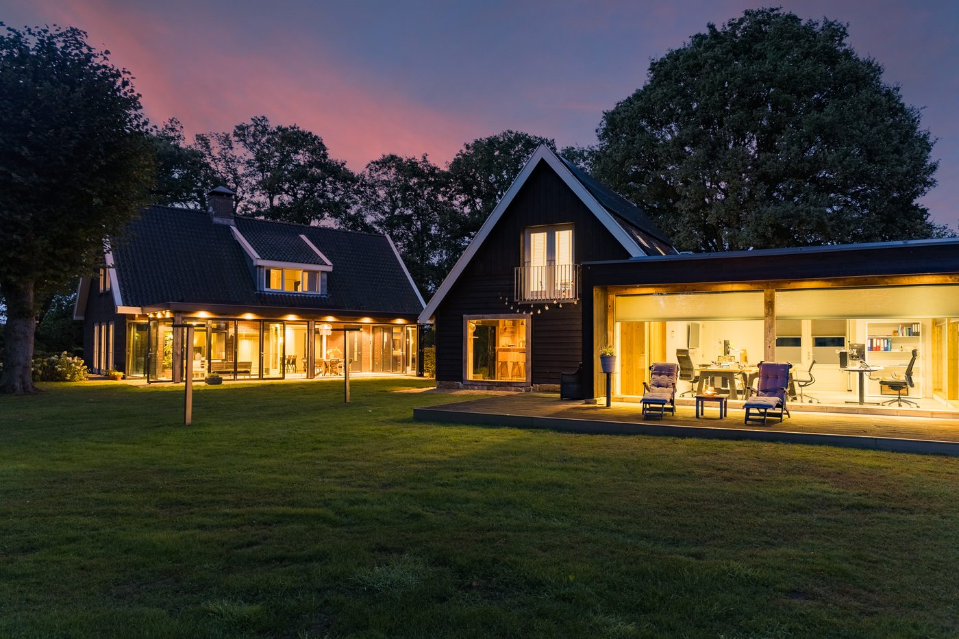 Het landhuis en het kantoorgebouw bij schemering, met verlichte glaspartijen