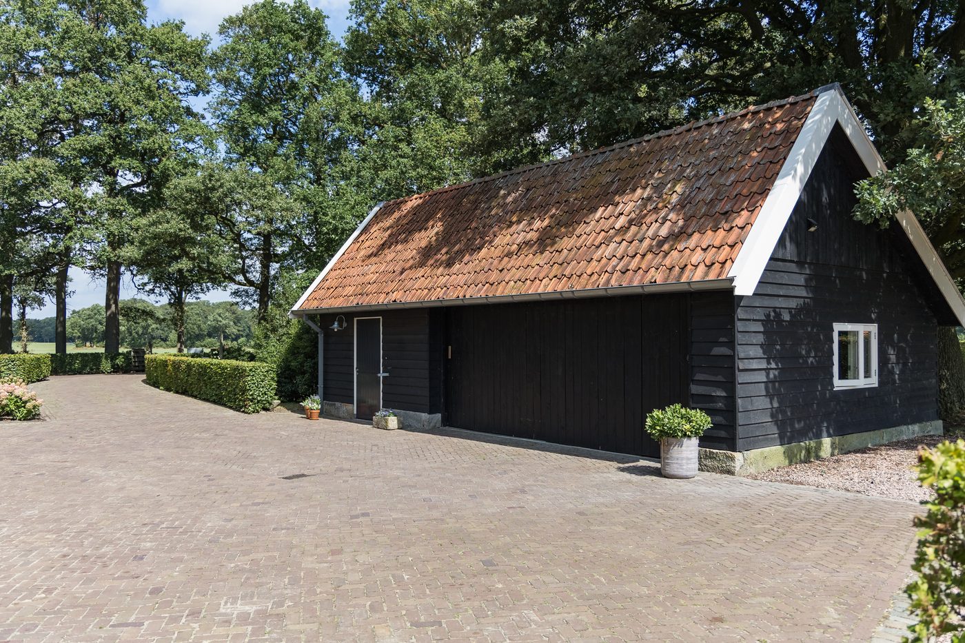 De kapschuur met pannendak en zwarte houten gevels, aan het klinkerplein