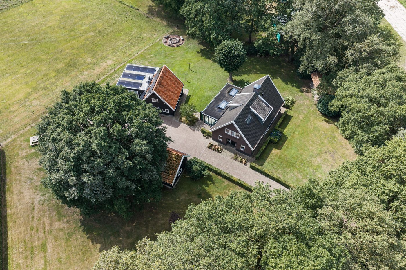 Luchtfoto van het erf: het landhuis, het kantoorgebouw en de kapschuren tussen de eikenbomen