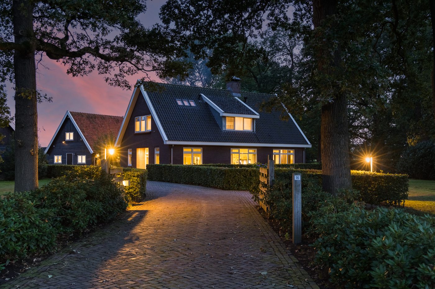 De verlichte oprit naar het landhuis bij schemering