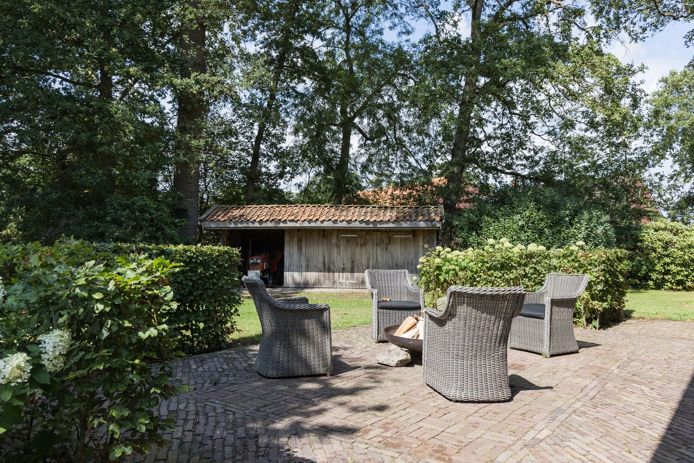 Zitplek op het terras bij de schuur, onder de eikenbomen