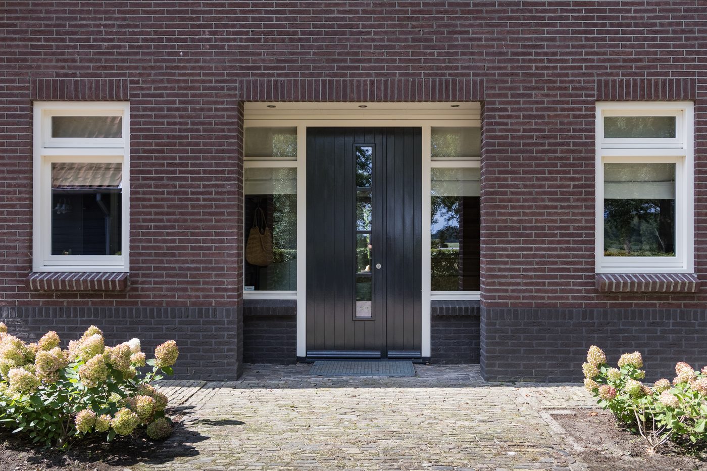 De voordeur van het landhuis met hortensia's in de border